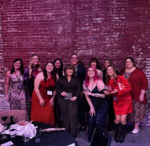 ADsmith team dressed up and posed for a picture holding their ADDY awards